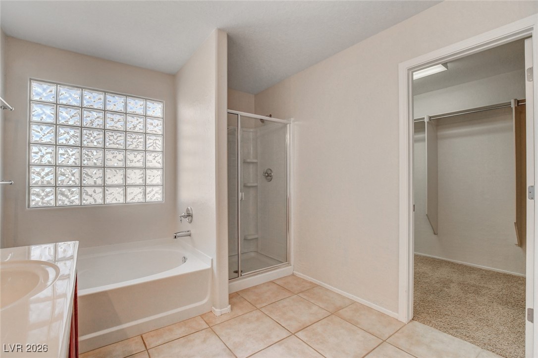 2460 Rue Bienville Way Henderson, NV 89044 - Photo 34 of 50 Full bath featuring a walk in closet, a stall shower, a garden tub, vanity, and light tile patterned floors