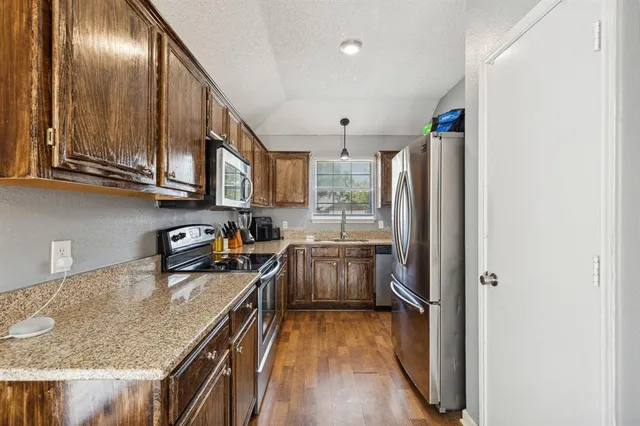 a kitchen with granite countertop a refrigerator stove top oven and sink