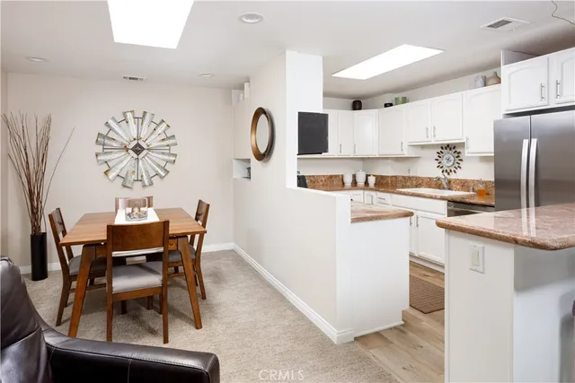 a kitchen with stainless steel appliances kitchen island a table chairs and a refrigerator