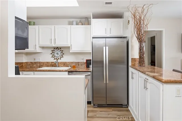 a kitchen with stainless steel appliances granite countertop a refrigerator a stove and white cabinets