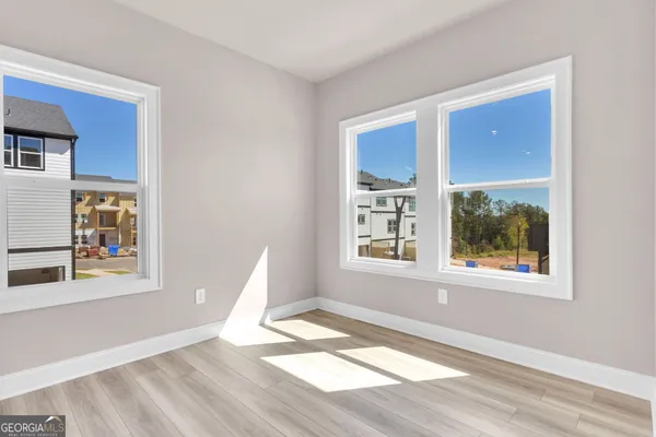 a view of an empty room with wooden floor and a window