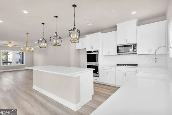 a large kitchen with kitchen island a stove a sink a center island and wooden floor