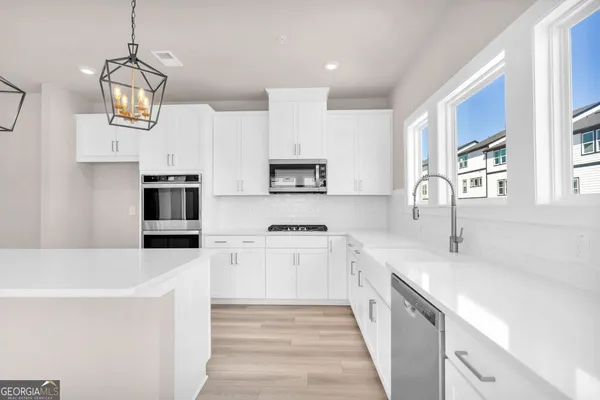 a kitchen with stainless steel appliances a stove top oven a sink a refrigerator white cabinets and wooden floor