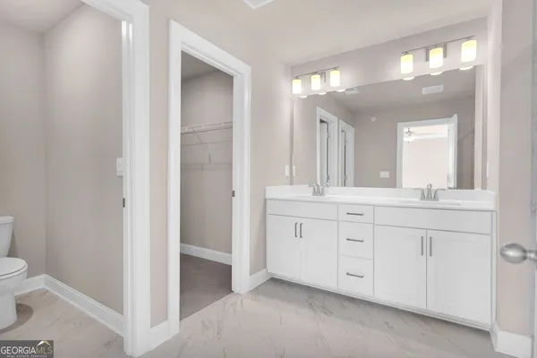a spacious bathroom with a granite countertop sink a toilet and a mirror