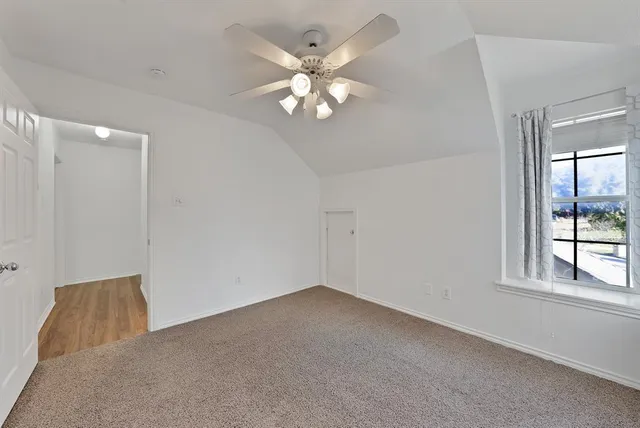 an empty room with windows and chandelier fan
