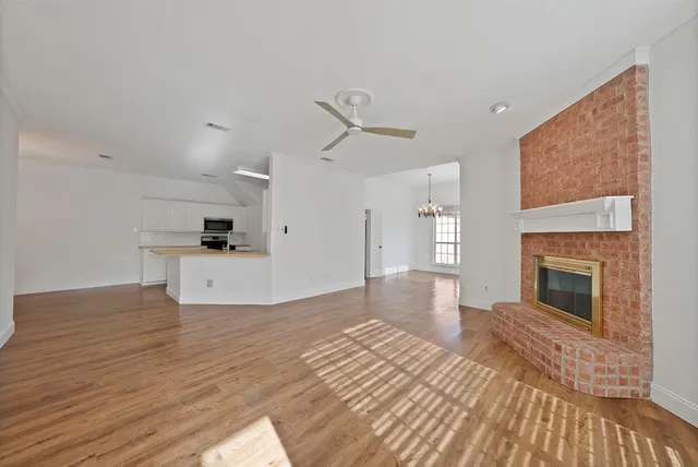 a view of empty room with wooden floor and kitchen view