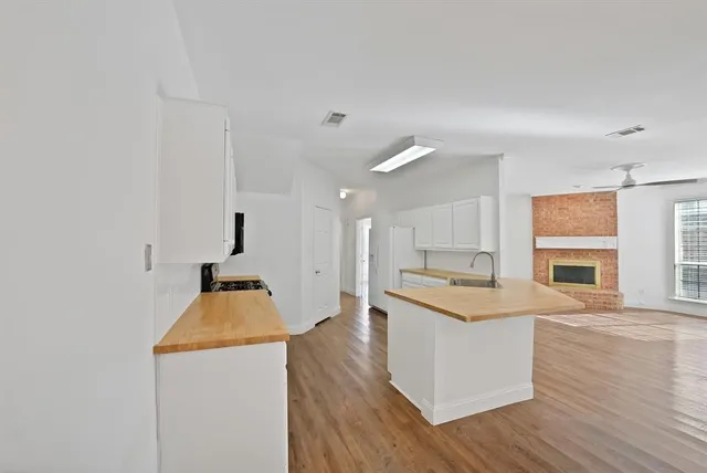 a kitchen with stainless steel appliances granite countertop a stove a sink and white cabinets with wooden floor