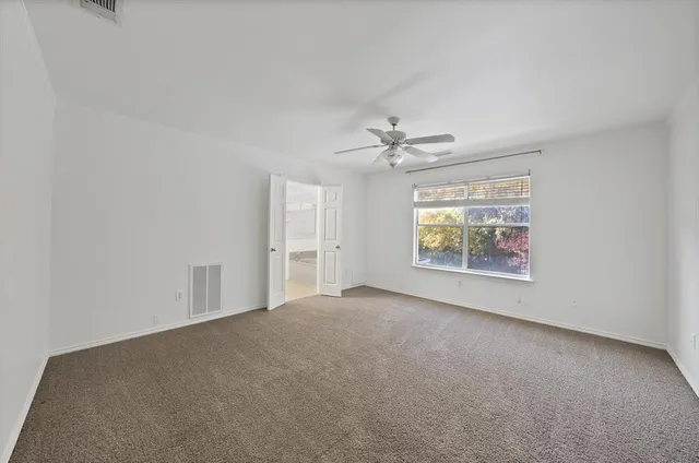 an empty room with windows and chandelier fan