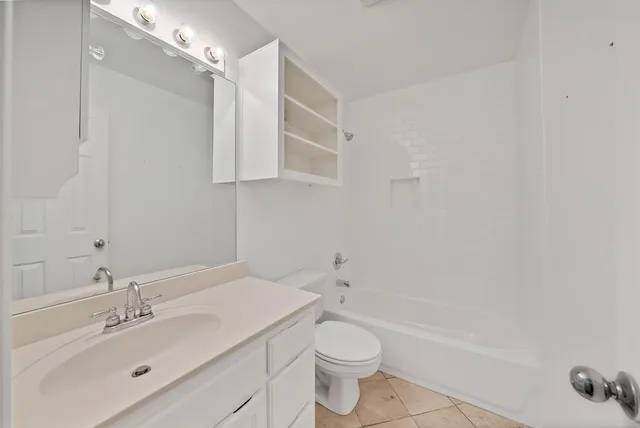 a bathroom with a bathtub shower sink vanity and toilet