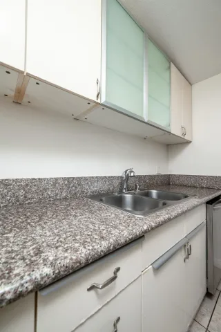 a kitchen with granite countertop a sink and a white cabinets