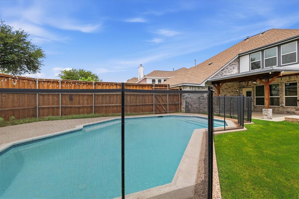 4545 Ridgepointe Drive The Colony, TX 75056 - Photo 12 of 37 Backyard featuring a built-in swimming pool with a safety barrier, surrounding aggregate concrete decking, and a covered patio area with exposed wood beams