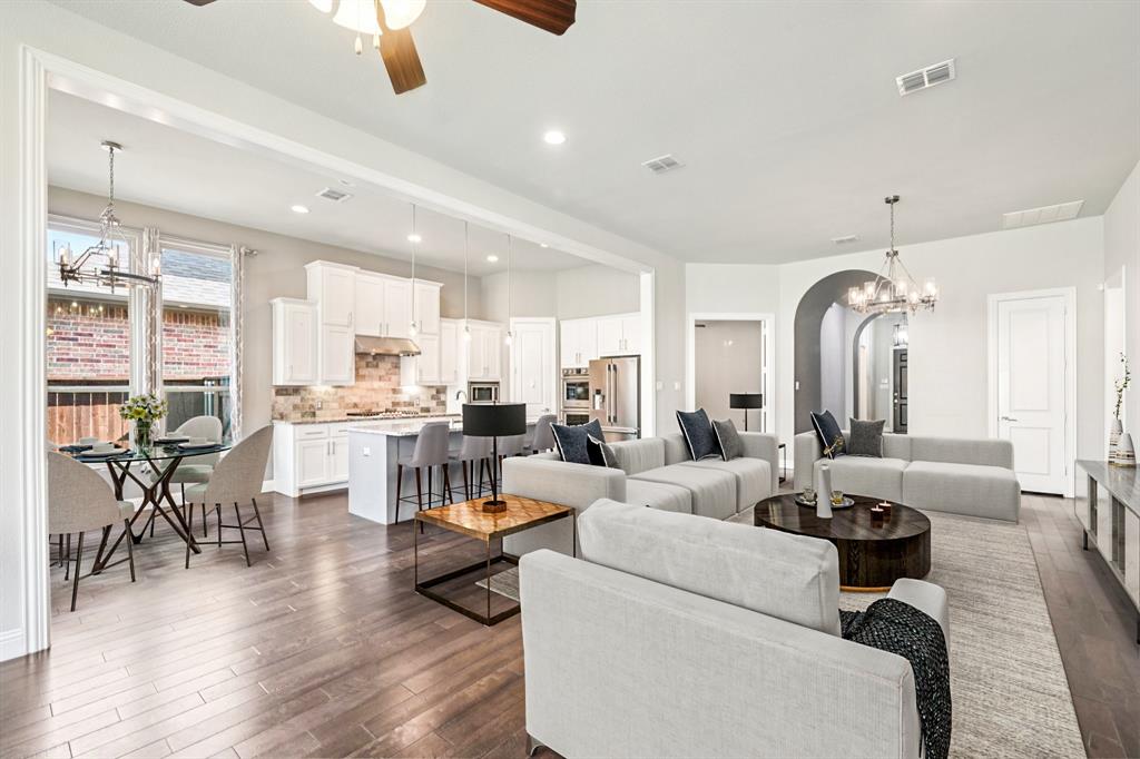 a living room with furniture kitchen view and a chandelier