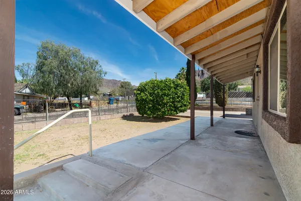 a backyard of a house with table and chairs under an umbrella