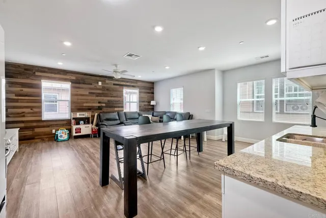 a kitchen with stainless steel appliances granite countertop a stove a refrigerator a dining table and chairs with wooden floor