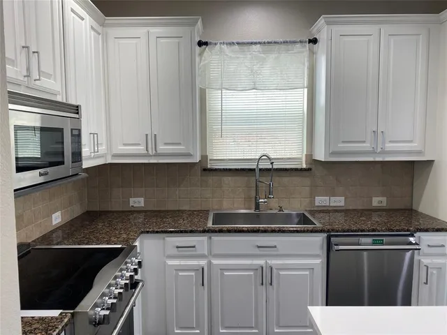 a kitchen with stainless steel appliances granite countertop a stove a sink and a microwave