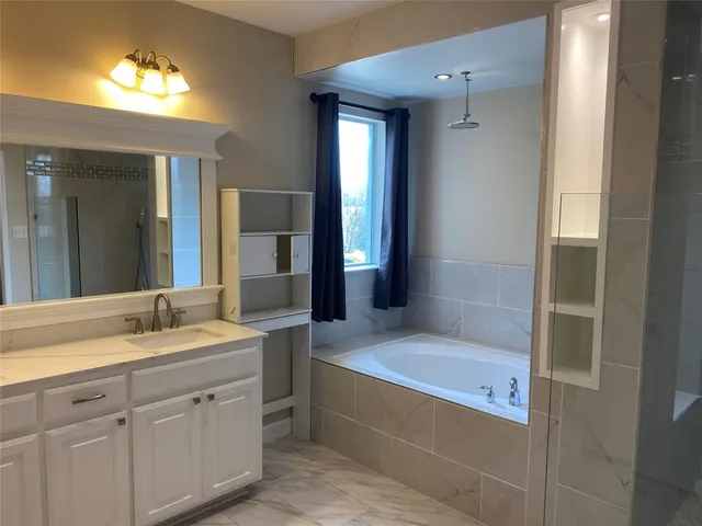 a bathroom with a tub a sink and a mirror