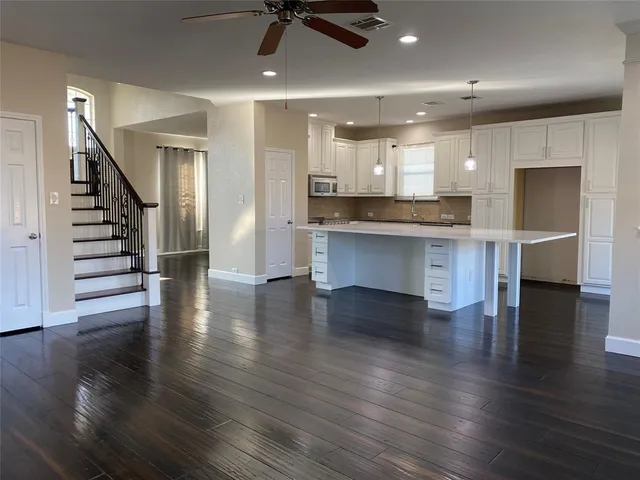 an open kitchen with white cabinets wooden floor and appliances