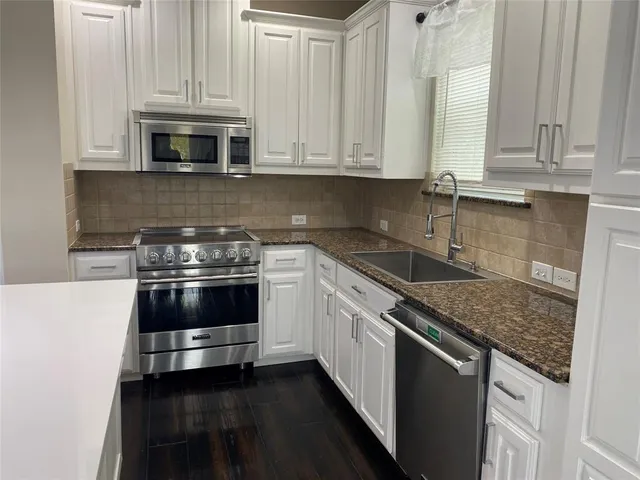 a kitchen with stainless steel appliances granite countertop white cabinets and a stove