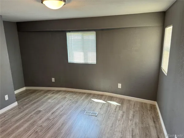 an empty room with wooden floor and windows