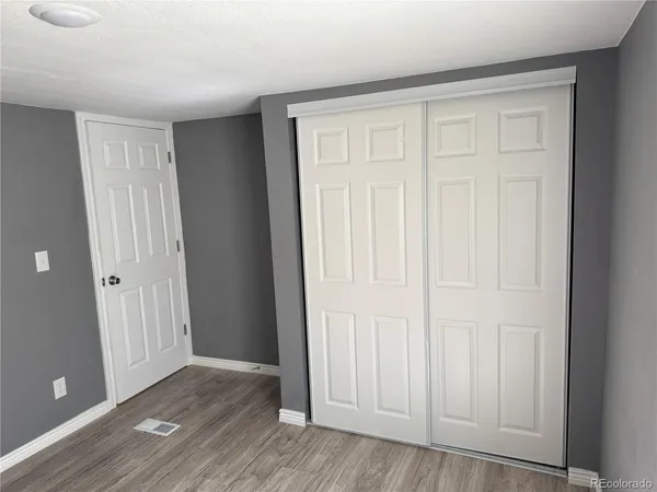 an empty room with wooden floor and closet area