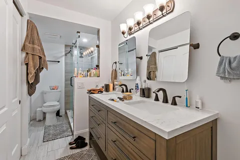 a bathroom with a sink a toilet a mirror and shower