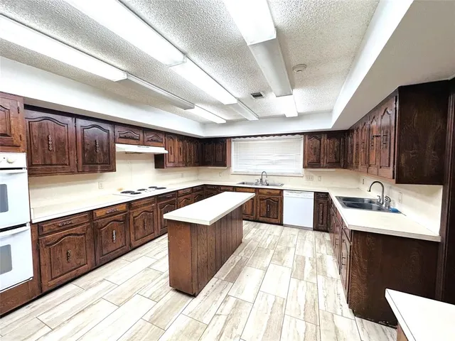 a large kitchen with stainless steel appliances kitchen island granite countertop a large counter top space a sink a stove and cabinets