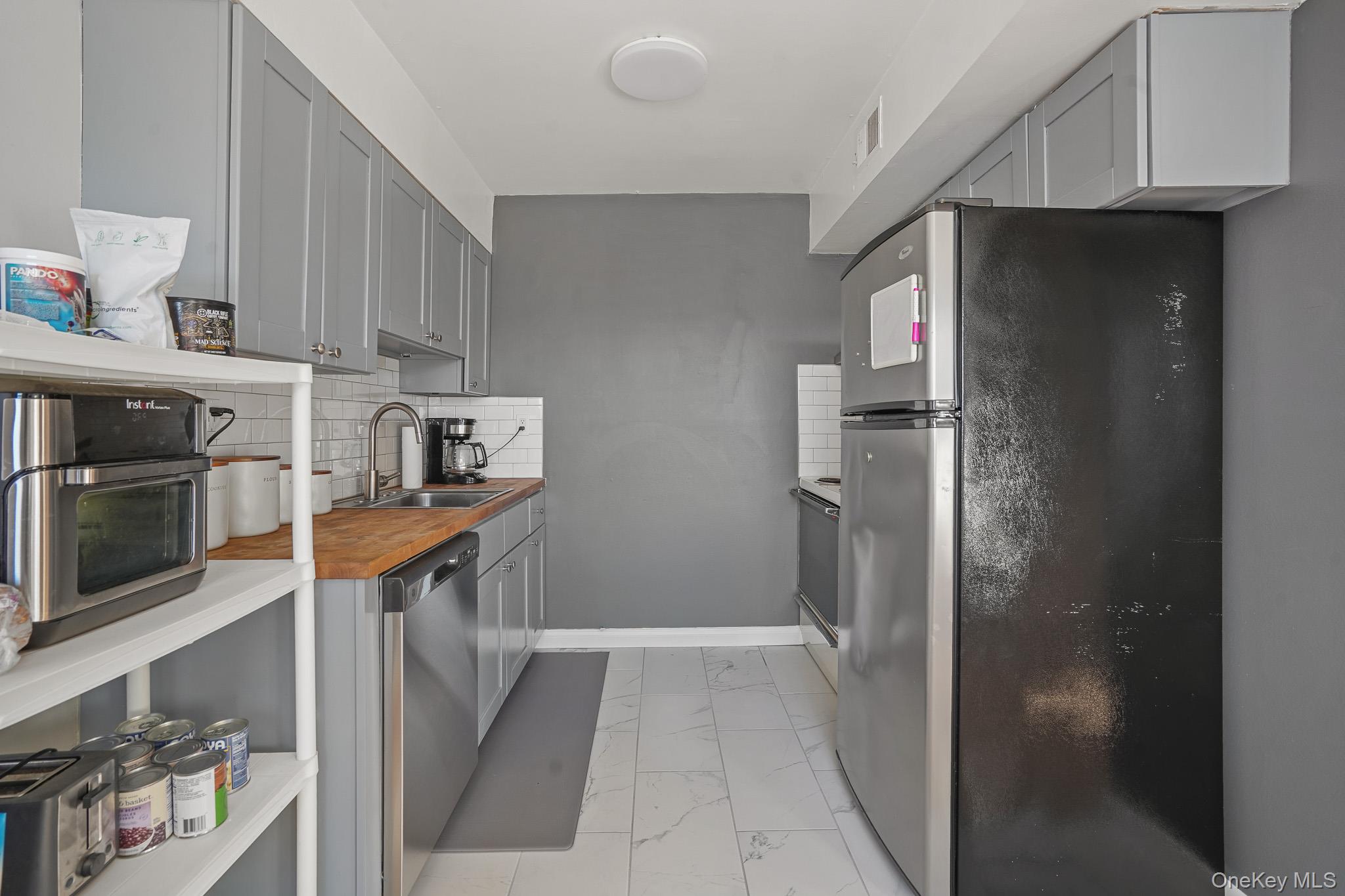 26 Cooper Road, Unit 411 Poughkeepsie, NY 12603 - Photo 7 of 17 Kitchen with gray cabinetry, stainless steel appliances, light marble finish flooring, tasteful backsplash, and wooden counters