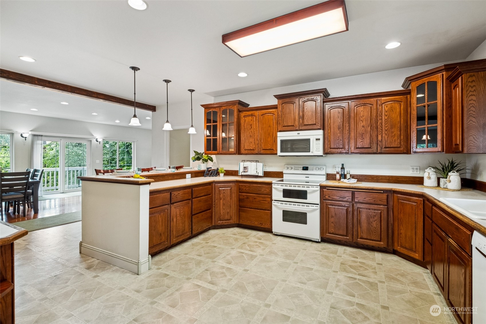 22601 Military Road South SeaTac, WA 98198 - Photo 6 of 40 a large kitchen with stainless steel appliances granite countertop a stove top oven a sink dishwasher a dining table and chairs with wooden cabinets
