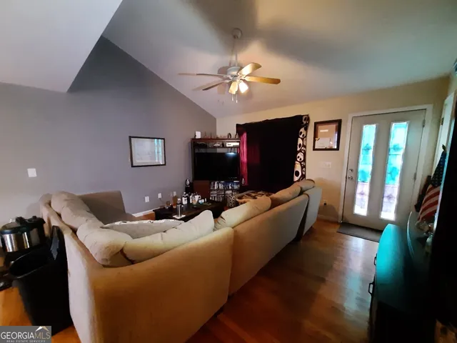 a living room with furniture a flat screen tv and a refrigerator