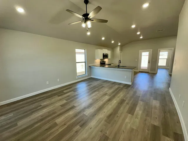 a view of a big room with wooden floor and a kitchen