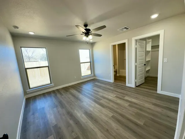 an empty room with wooden floor and windows