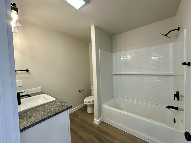 a bathroom with a granite countertop sink toilet and shower