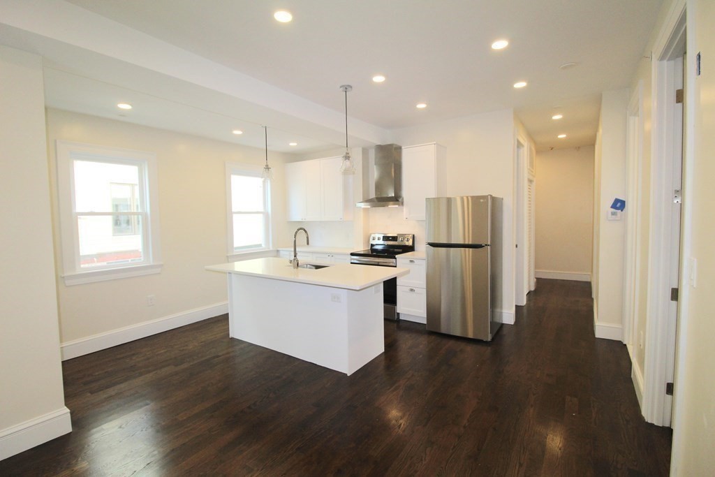 a kitchen with stainless steel appliances refrigerator wooden floor and window