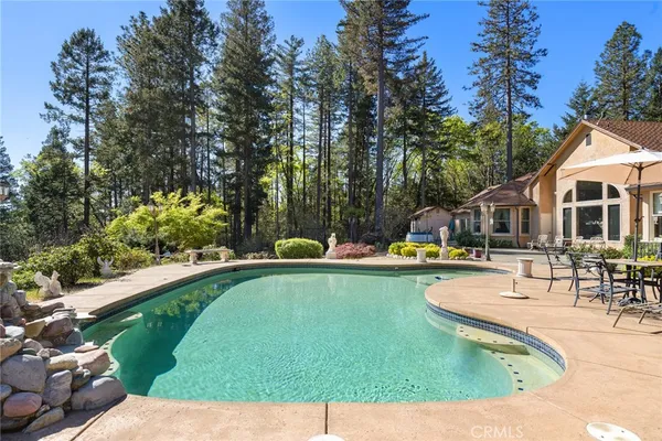 a view of backyard with swimming pool and seating space