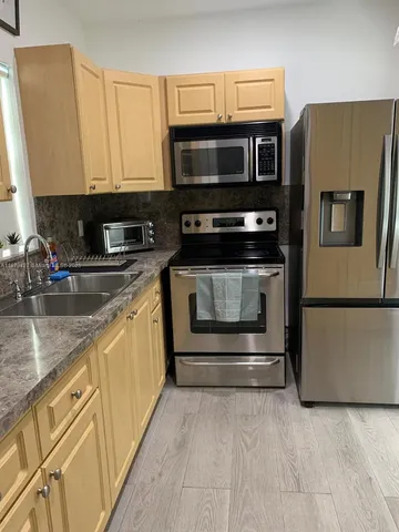 a kitchen with stainless steel appliances granite countertop a refrigerator microwave and sink