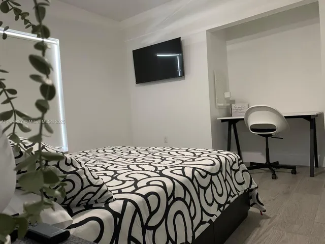 a bedroom with a bed and a a flat tv screen