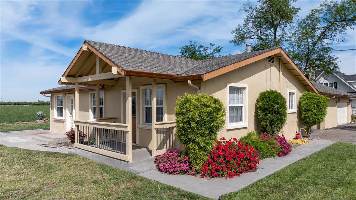 607 East Keyes Road Ceres, CA 95307 - Photo 25 of 46 view of property exterior featuring a yard, stucco siding, covered porch, and roof with shingles