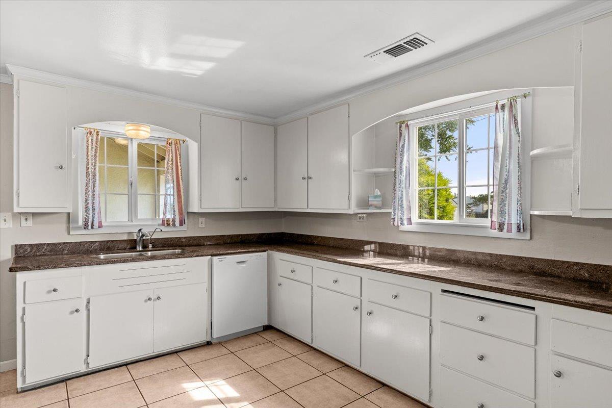 607 East Keyes Road Ceres, CA 95307 - Photo 34 of 46 kitchen featuring open shelves, white dishwasher, white cabinets, light tile patterned floors, and dark stone countertops
