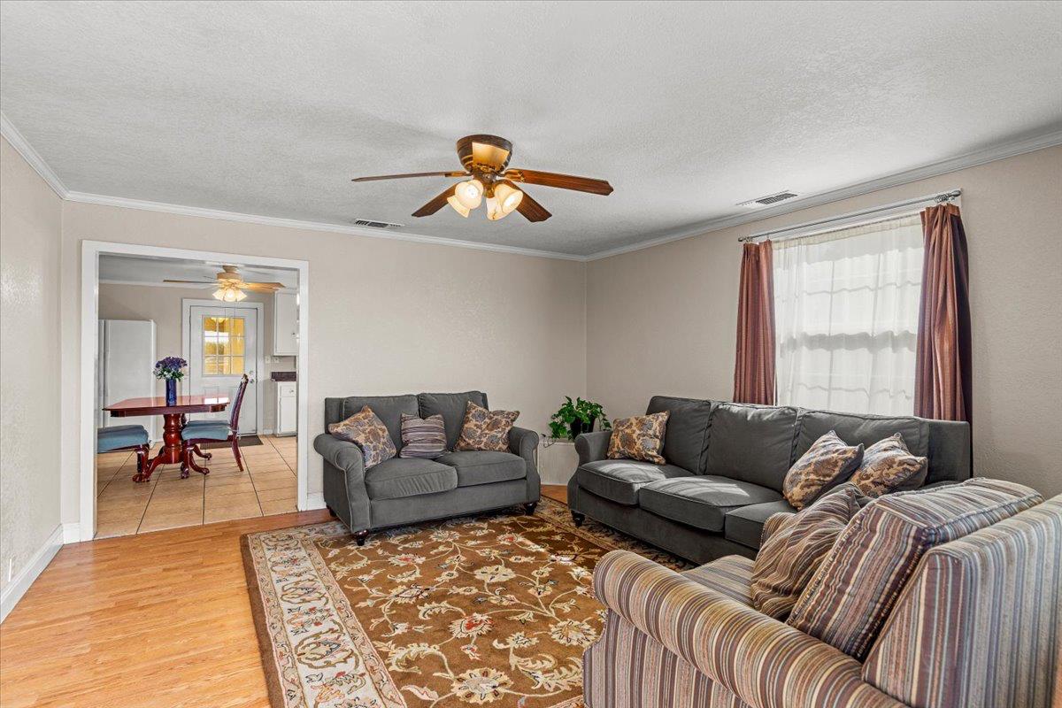 607 East Keyes Road Ceres, CA 95307 - Photo 39 of 46 living room featuring light wood finished floors, a textured ceiling, ornamental molding, healthy amount of natural light, and a ceiling fan