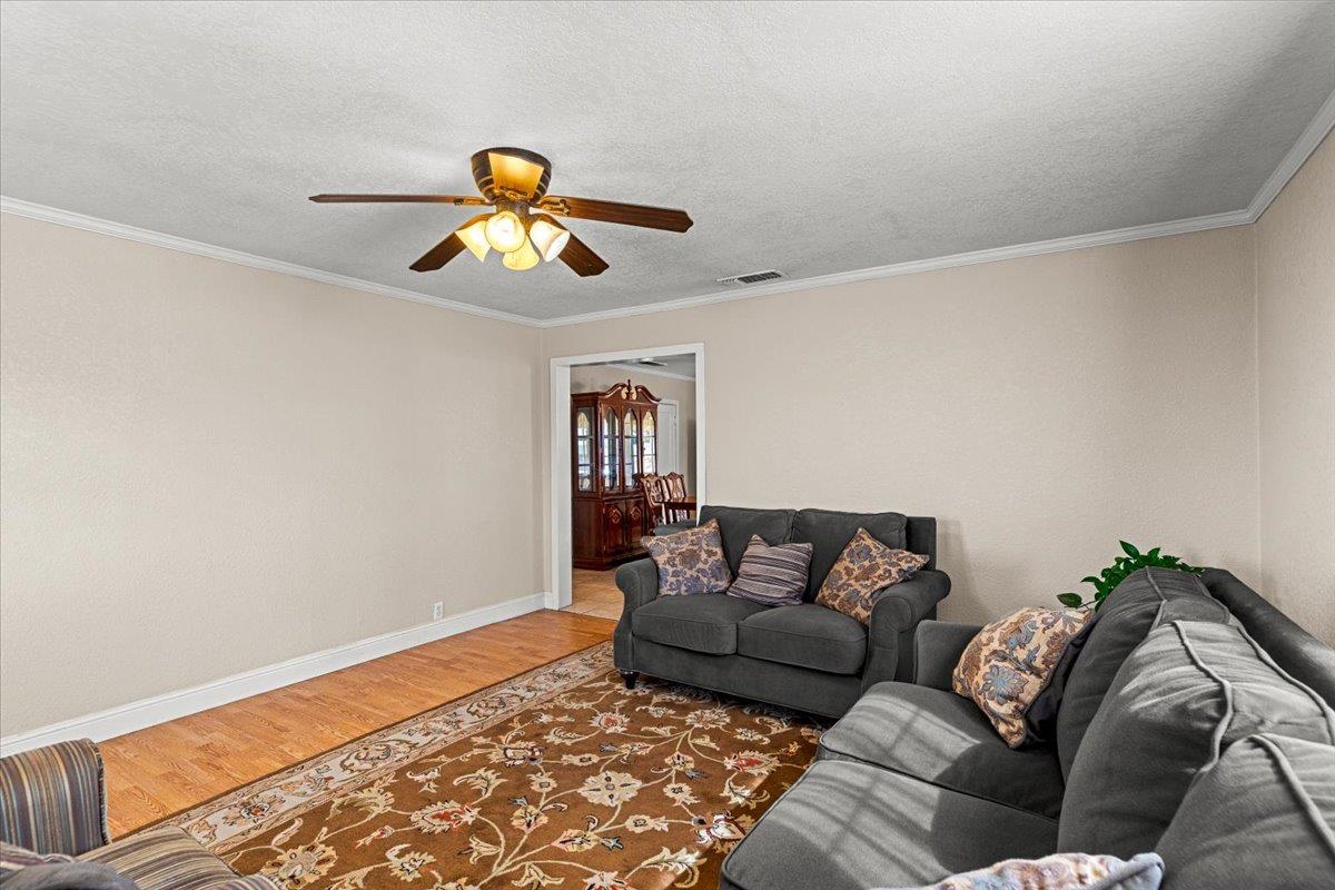 607 East Keyes Road Ceres, CA 95307 - Photo 44 of 46 living area featuring wood finished floors, crown molding, a ceiling fan, and a textured ceiling