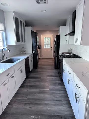 a large kitchen with cabinets wooden floor and stainless steel appliances