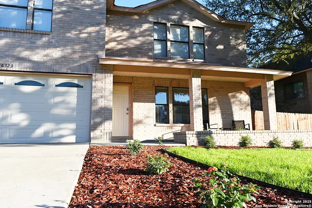 a view of a house with a yard and a large tree