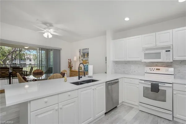 a kitchen with white cabinets and white appliances