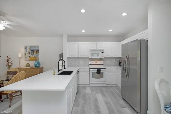 a kitchen with a sink a stove a refrigerator and white cabinets