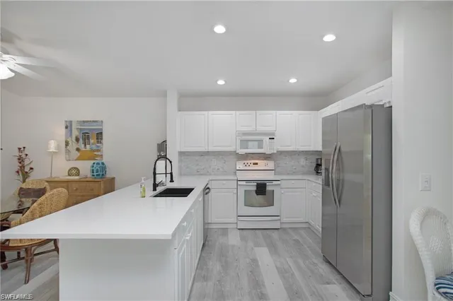 a kitchen with a sink a stove a refrigerator and white cabinets