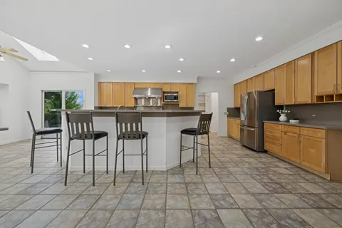 a kitchen with stainless steel appliances granite countertop a stove a sink a microwave a dining table and chairs