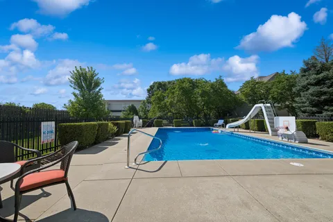 a view of a swimming pool with a patio and fire pit