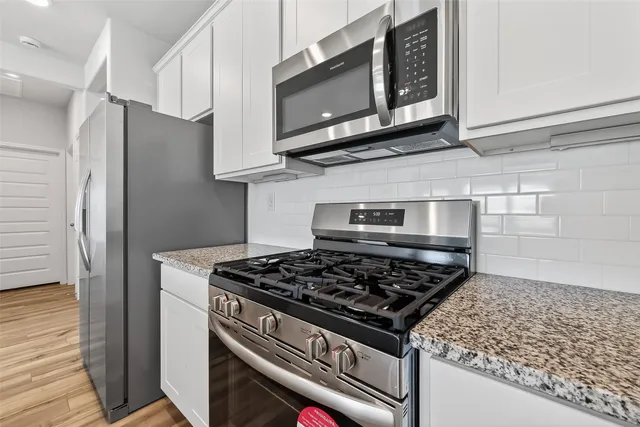 a kitchen with stainless steel appliances granite countertop cabinets and a stove top oven