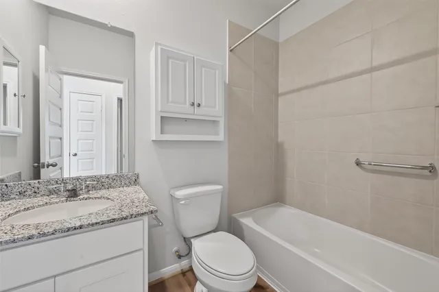 a bathroom with a granite countertop toilet sink and mirror