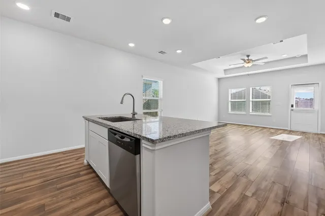 a kitchen with stainless steel appliances granite countertop a sink and wooden floor